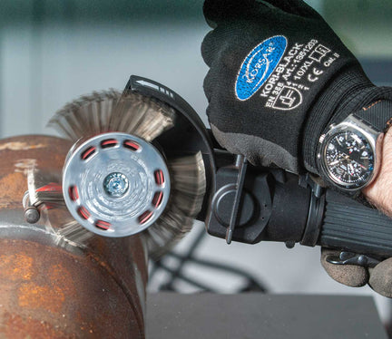 Industrial worker using an angle grinder on a metal pipe