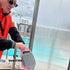 Ship Cleaning Operative fits a SurfSaviour microfiber glove onto their hand for cleaning pool-side shower